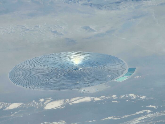 A fascinating aerial view of a solar power plant with reflective panels under a cloudy sky for curious minds.