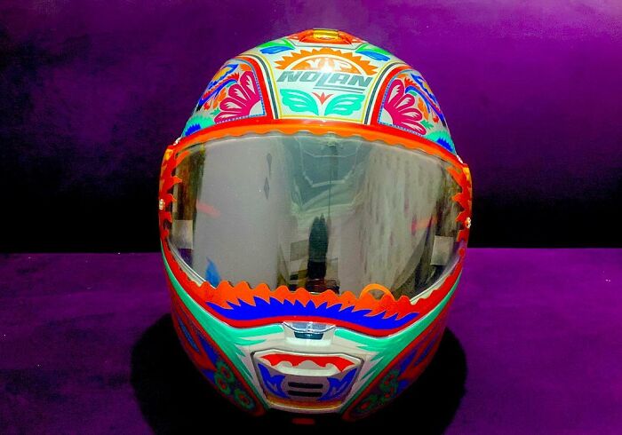 Colorful, intricate patterns painted on a motorcycle helmet showcasing stunning works of art by this artist.