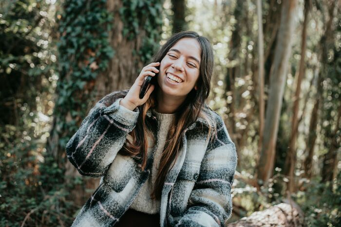 Young woman smiling and talking on phone outdoors, reflecting on dark and heartfelt secrets people keep from lovers.