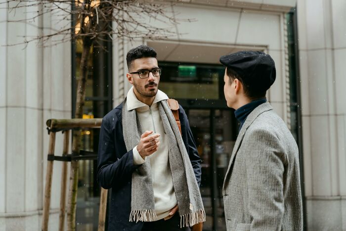 Two men having a conversation outside a building during winter, illustrating an unpopular opinions poll discussion.